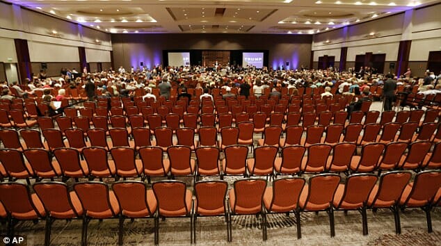 An empty conference hall with rows of red chairs, seen from the stage